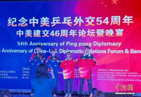 当地时间12月22日，纪念中美“乒乓外交”54周年、中美建交46周年论坛暨晚宴在美国洛杉矶举行。图为中国乒乓球世青赛冠军李和宸和胡一出席中国乒乓球队和美国乒乓球队交换队服仪式。　中新社记者 张朔 摄