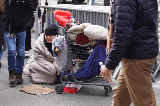 2025年12月31日,在美国纽约街头,无家可归者坐在街边等待帮助。新华社记者张凤国摄